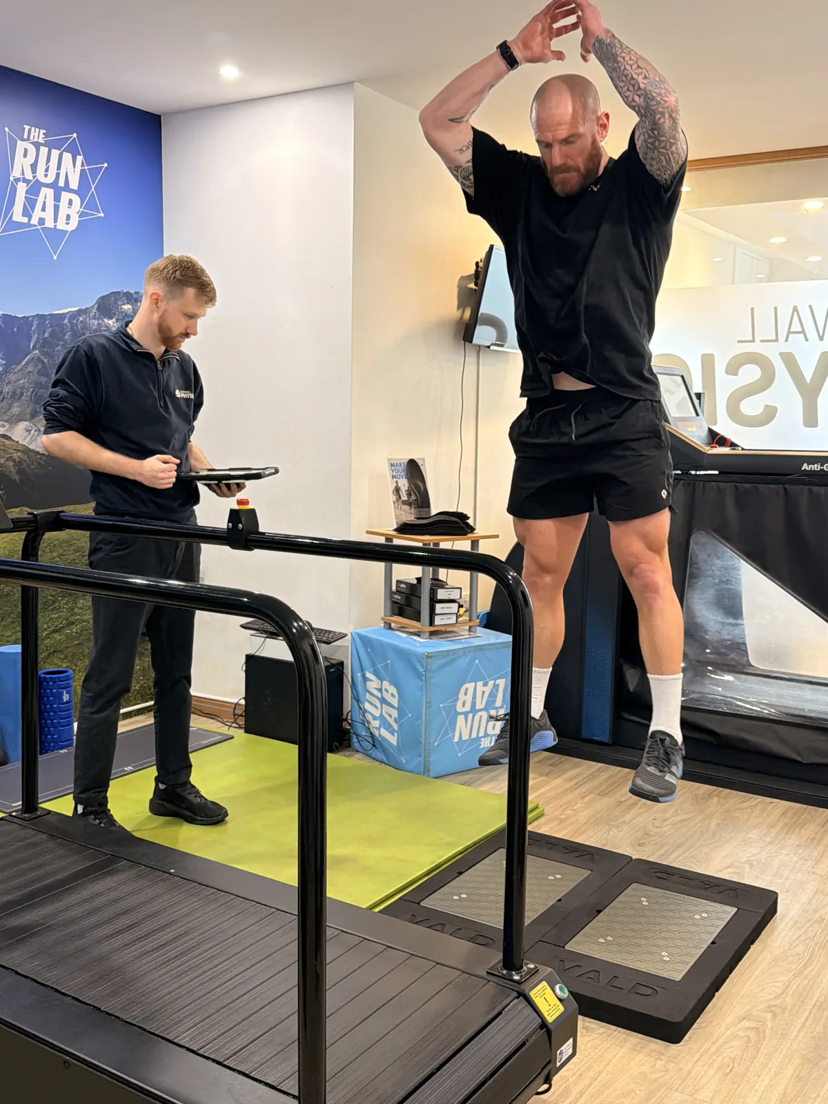 An athlete performing a jump test on VALD® force plates in The Run Lab® while a Cornwall Physio therapist records the result