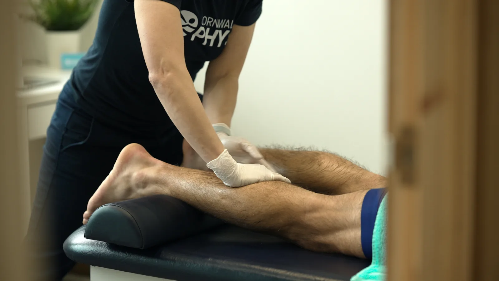 A Cornwall Physio therapist giving hands-on treatment to an athlete's calf and Achilles
