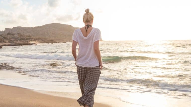 Person walking calmly on a Cornwall beach, representing recovery from nervous system dysregulation.